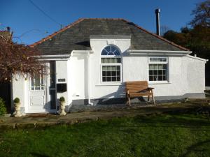 科尔温湾Delfryn Holiday Cottage的前面有长凳的白色房子
