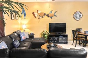 南帕诸岛Kingfisher的客厅配有黑色真皮沙发和平面电视。