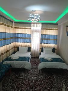 布哈拉Hotel Guest House GOLDEN DEGREZ的绿灯客房内的两张床