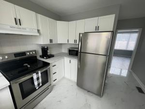渥太华Casa LACK - Tranquila Suites 2的厨房配有不锈钢冰箱和白色橱柜