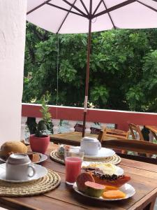 皮拉尼亚斯Pousada Maria Bonita - Piranhas, Alagoas.的一张带食物盘子和雨伞的木桌