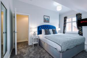 考文垂Westwood Lodge Serviced Apartment的一间卧室配有一张大床和蓝色床头板