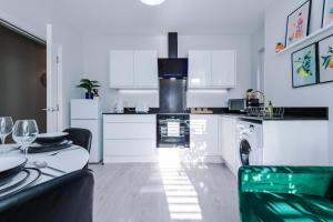 考文垂Beechwood Lodge Serviced Apartment的厨房配有白色橱柜、桌子和炉灶。