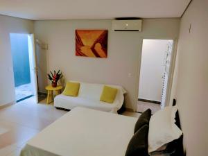 瓜鲁雅Flat Ideal Guarujá - Apto Studio Mobiliado, Ar-Condic e Cozinha Completa的一间带两张床和一张沙发的客厅