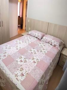 波苏斯-迪卡尔达斯Aconchego Poços de Caldas的一张床上有粉红色和白色的被子