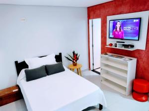瓜鲁雅Flat Ideal Guarujá - Apto Studio Mobiliado, Ar-Condic e Cozinha Completa的卧室配有白色的床和墙上的电视