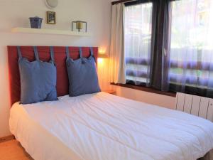 瓦尔Appartement Vars, 2 pièces, 4 personnes - FR-1-330B-129的一间卧室配有一张带蓝色枕头的床和一扇窗户。