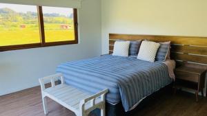 拉恩塞纳达Casa Familiar Puerto Varas的一间卧室配有一张床、一张长凳和一个窗户。