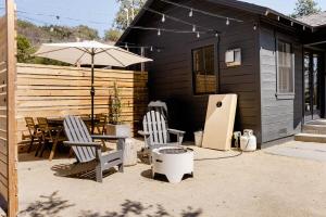 阿罗约格兰德Wild Hair Studio-stylish Farm Stay W Ev Charger的庭院配有两把椅子、一张桌子和一把遮阳伞
