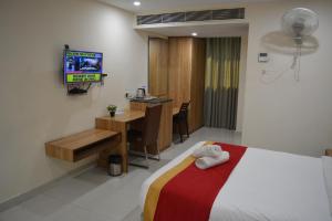 维沙卡帕特南Hotel Ambicas Grand的酒店客房配有一张床、一张书桌和一台电视。