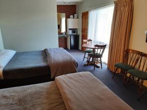 吉朗阿伯茨伍德汽车旅馆的酒店客房带一张床、一张桌子和椅子