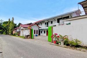 BangkinangSPOT ON 91950 Guest House TekNong Syariah的一条空的街道,旁边是白色的建筑,带有绿色的口音