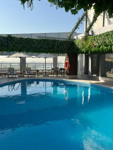 多哈Gloria Hotel & Suites Doha的一个带椅子和遮阳伞的大型蓝色游泳池