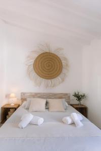 比利亚霍约萨VILASUITES Beach, Sand & Menta的卧室配有白色床,墙上挂有草帽