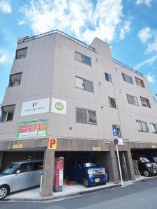 广岛PINE TREE HOTEL的一座大型建筑,前面停有两辆车