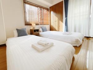 广岛PINE TREE HOTEL的客房内的两张床和毛巾