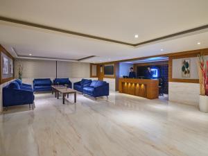 钦奈Essentia Premier Hotel Chennai OMR的大堂设有蓝色椅子、桌子和电视。