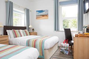 尚克林卢康蓓庄园乡间别墅酒店的一间卧室配有两张床、一张桌子和两个窗户。