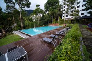 云顶高原4-7 Pax Genting View Resort Kempas Residence -Free Wifi, Netflix And Free Parking的一座带躺椅的游泳池位于大楼旁