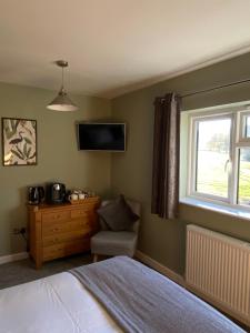 WeobleyMarshpools Bed & Breakfast - Licensed near Weobley village的卧室配有一张床,墙上配有电视。
