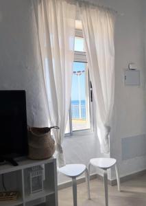 加尔达尔Apartamentos MENBAU的客厅设有2张白色凳子和1扇窗户