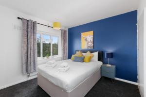 西德雷顿Brambles House West Drayton 3 Bedroom House with parking By MDPS的蓝色的卧室设有一张大床和一个窗户
