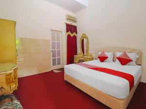 占碑市OYO 2899 Ardilia Bandara Syariah的一间卧室配有一张带红色和白色枕头的大床