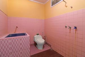 占碑市OYO 2899 Ardilia Bandara Syariah的粉红色的浴室设有卫生间和浴缸。