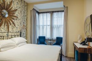 斯坦福德王冠酒店的酒店客房,配有一张床和两张蓝色椅子