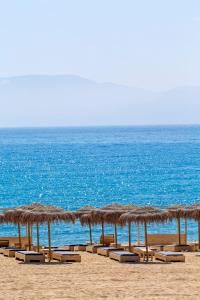 迈洛波塔斯狄俄尼索斯海滨度假酒店的海滩上一排草伞和椅子