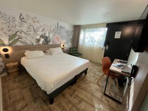 维特罗勒Kyriad Vitrolles Aéroport Marseille的酒店客房带一张床铺、一张书桌和一间卧室