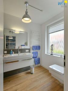 于斯德Haus Inselrose Ferienwohnung Wildrose的一间带水槽和卫生间的浴室以及窗户。