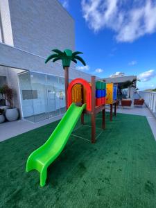 邦比尼亚斯Vila do Centro Apart Hotel的草坪上带绿色滑梯的游乐场