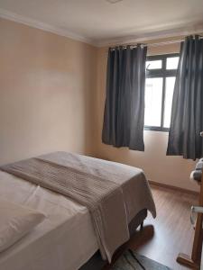 库里提巴Apartamento Conforto的一间卧室配有床和带窗帘的窗户