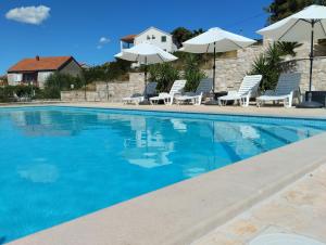 斯普利特卡Villa Sanja, Splitska的一个带椅子和遮阳伞的游泳池