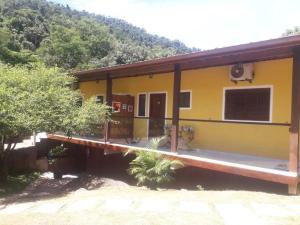 伊利亚贝拉Chalés Azuleto - Ilhabela的黄色的房子,有门廊和山