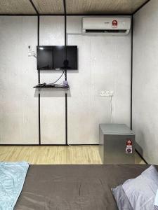 巴东勿刹Padang Besar Rainbow Cabin Homestay的一间卧室配有一张床,墙上配有电视