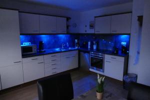 巴特拉斯费Ferienwohnung Am Sonnenhang Blecher的厨房配有白色橱柜和蓝色灯光