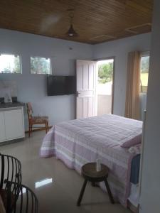 皮涅拉Vila Sabará的一间卧室配有一张床铺和一张桌子,还设有一间厨房
