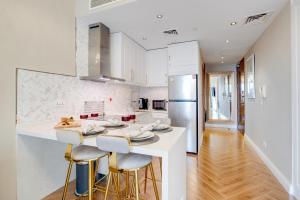 迪拜Luxury Apt - Rooftop Pool - City View的厨房配有白色橱柜和带凳子的台面