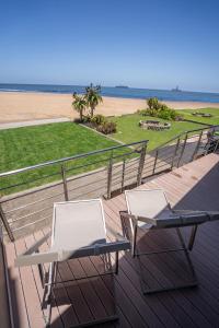 LangstrandDeja Blue Beachfront Villa, Newly renovated的甲板上配有两把椅子和一张桌子,俯瞰着海滩