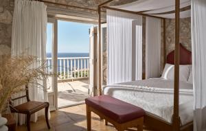圣尼古拉奥斯奥佛斯别墅酒店的一间卧室设有一张天蓬床和一个海景阳台