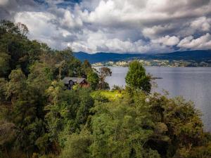 帕斯托Habitaciòn Floraciòn con vista a la Laguna的水体旁山丘上的房屋