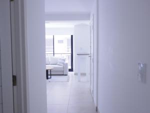 马德普拉塔5C Departamento de dos ambientes, por escalera.的白色的走廊,配有沙发和桌子