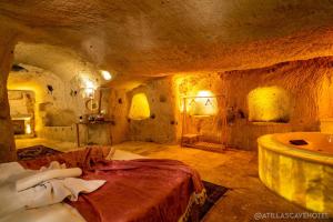 内夫谢希尔Atilla's Cave Hotel的一间洞穴内的卧室,配有一张床和一个浴缸