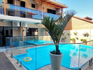 弗洛里亚诺波利斯Pousada Casa Da Praia的一座房子,前面有一座游泳池和一棵棕榈树