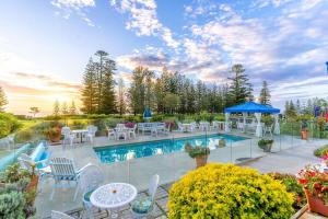 彭特派因Sunset Villa Norfolk Island - a Mediterranean inspired villa的一个带白色桌椅和蓝色遮阳伞的游泳池