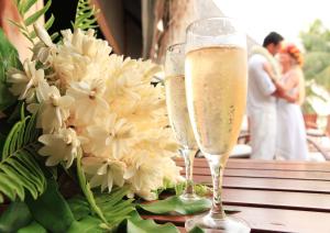 提克豪Le Tikehau by Pearl Resorts的两杯香槟,坐在一张带鲜花的桌子上