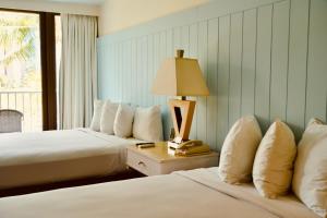 檀香山Hotel La Croix的酒店客房设有两张床和一张桌子上的台灯。