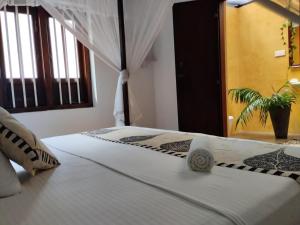 米瑞莎魅力米瑞莎酒店的一间卧室配有白色床单和植物